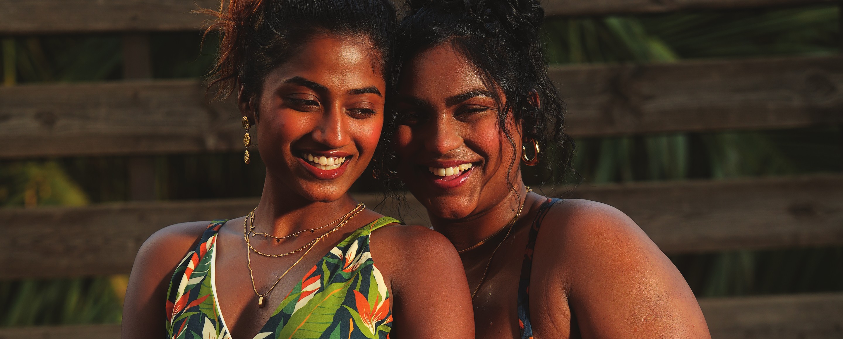 Two women in printed MAG swimwear standing together in a pool at golden hour